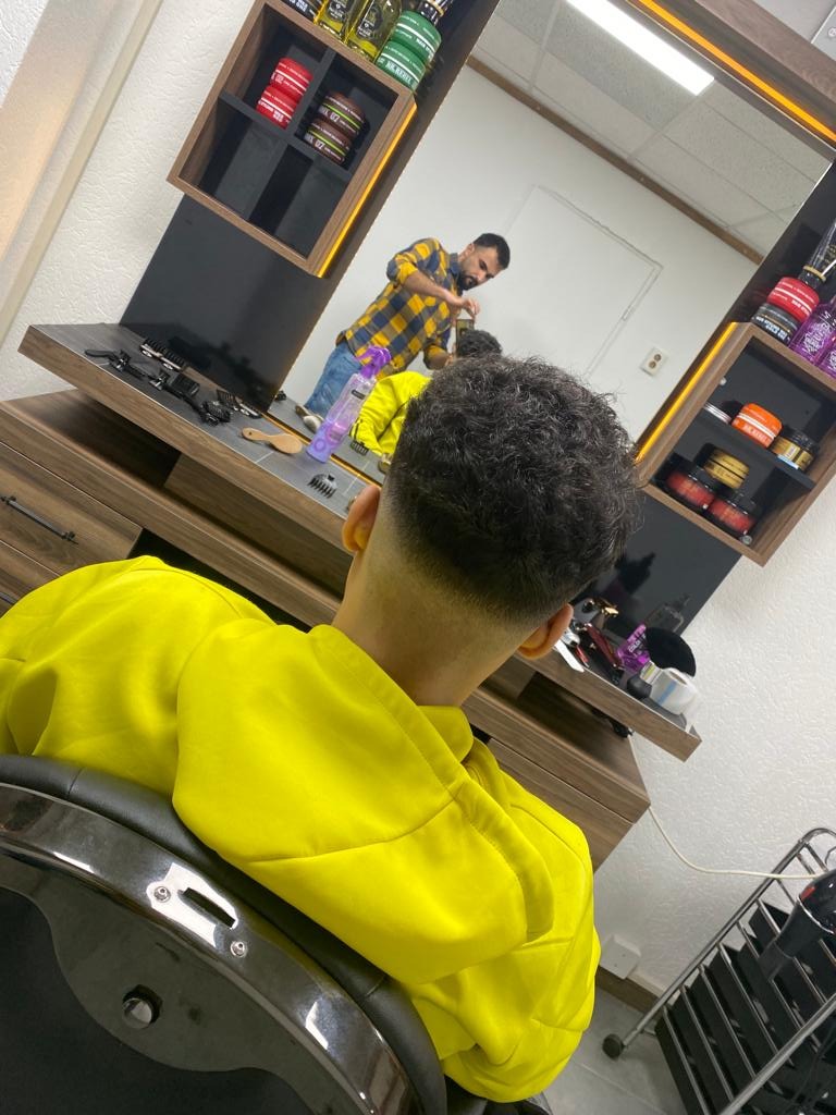 Ilias aan het werk bij Kapsalon Paris, gezien in de spiegel